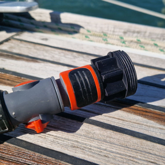 A green garden hose attached to a deck filler fitting